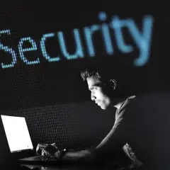 Mężczyzna pracuje przy laptopie, nad nim świeci napis "Security". Dowiedz się, jak zahasłować plik Excel, by chronić swoje dane.