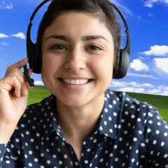 Uśmiechnięta kobieta w słuchawkach z mikrofonem, z klasycznym tłem "Bliss" z Windows XP. Dowiedz się, jak ustawić tło w Teams, by Twoje rozmowy były przyjemniejsze!