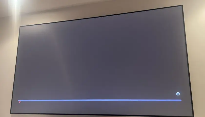 Szary ekran telewizora z niebieskim paskiem postępu i ikoną mikrofonu. Czekam na air play.
