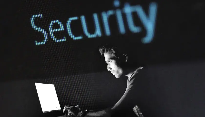 Mężczyzna pracuje przy laptopie, nad nim świeci napis "Security". Dowiedz się, jak zahasłować plik Excel, by chronić swoje dane.