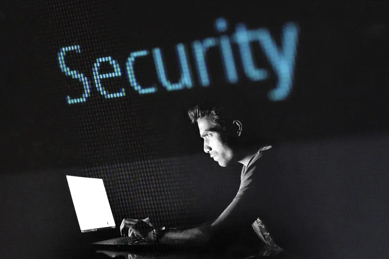Mężczyzna pracuje przy laptopie, nad nim świeci napis "Security". Dowiedz się, jak zahasłować plik Excel, by chronić swoje dane.