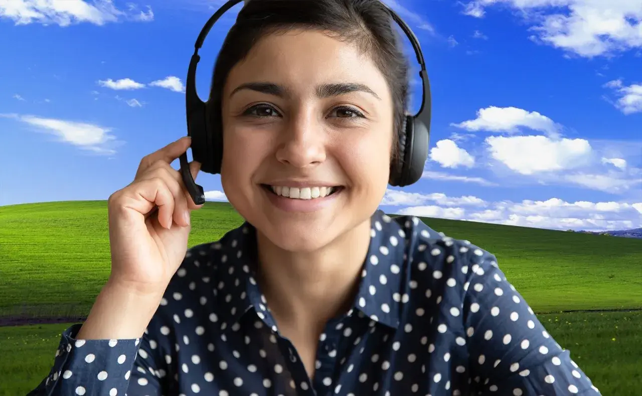 Uśmiechnięta kobieta w słuchawkach z mikrofonem, z klasycznym tłem "Bliss" z Windows XP. Dowiedz się, jak ustawić tło w Teams, by Twoje rozmowy były przyjemniejsze!